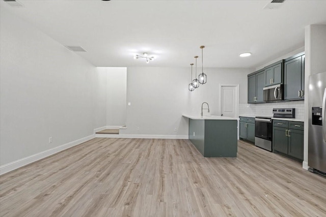 6305 Pebble Ave, Dallas, TX 75217 - kitchen featuring appliances with stainless steel finishes, backsplash, light hardwood / wood-style flooring, and pendant lighting