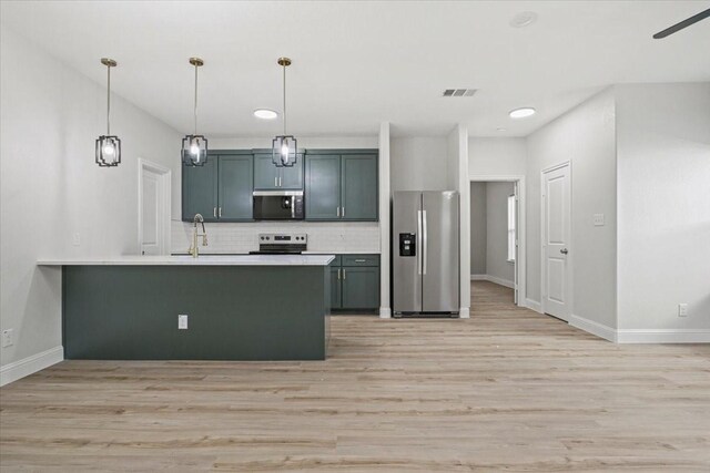 6305 Pebble Ave, Dallas, TX 75217 - kitchen featuring kitchen peninsula, appliances with stainless steel finishes, tasteful backsplash, pendant lighting, and light hardwood / wood-style floors
