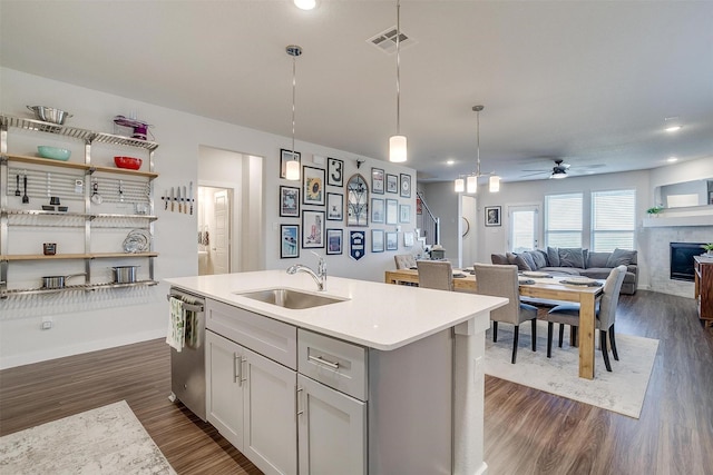 kitchen with sink, hanging light fixtures, stainless steel dishwasher, ceiling fan, and an island with sink