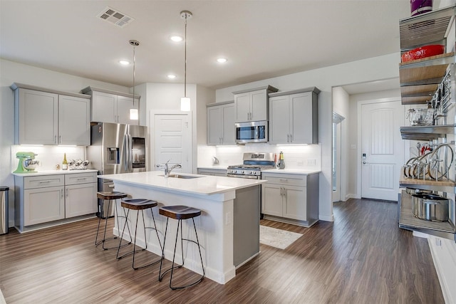 kitchen featuring a kitchen breakfast bar, an island with sink, dark hardwood / wood-style floors, and appliances with stainless steel finishes