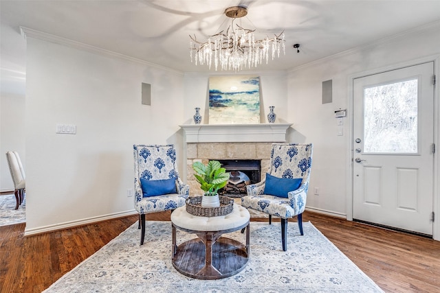 living area with a tile fireplace, crown molding, hardwood / wood-style floors, and a notable chandelier