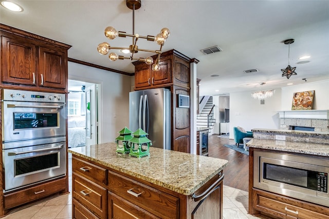 kitchen with appliances with stainless steel finishes, a center island, crown molding, and a notable chandelier