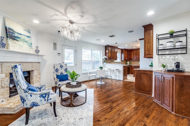 living room with dark hardwood / wood-style floors, ornamental molding, a fireplace, and an inviting chandelier