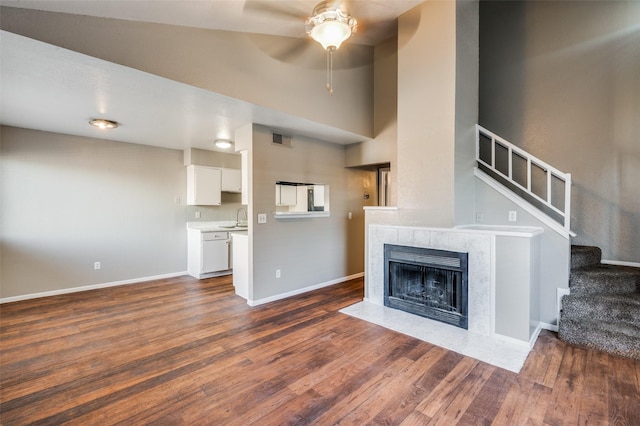 unfurnished living room with a fireplace, dark hardwood / wood-style flooring, ceiling fan, and sink