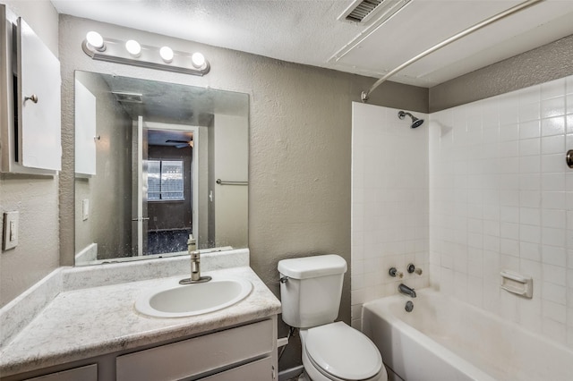 full bathroom with a textured ceiling, vanity, toilet, and tiled shower / bath