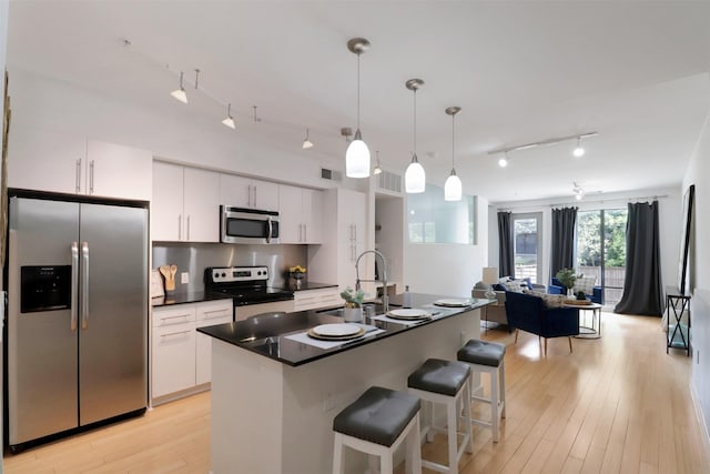 kitchen featuring white cabinets, appliances with stainless steel finishes, hanging light fixtures, and sink