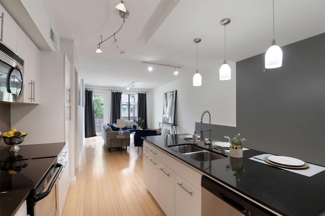 kitchen with stainless steel appliances, sink, decorative light fixtures, light hardwood / wood-style floors, and white cabinetry