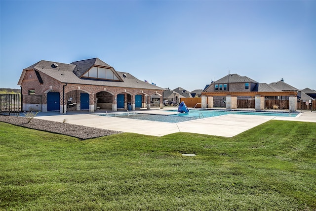 pool with a patio, a lawn, and fence