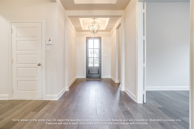 foyer entrance with a chandelier, a raised ceiling, dark wood finished floors, and baseboards