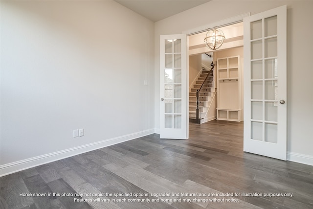 spare room featuring dark wood-style floors, french doors, an inviting chandelier, and baseboards