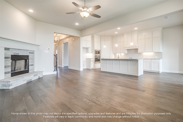 unfurnished living room featuring a fireplace, visible vents, ceiling fan, wood finished floors, and baseboards