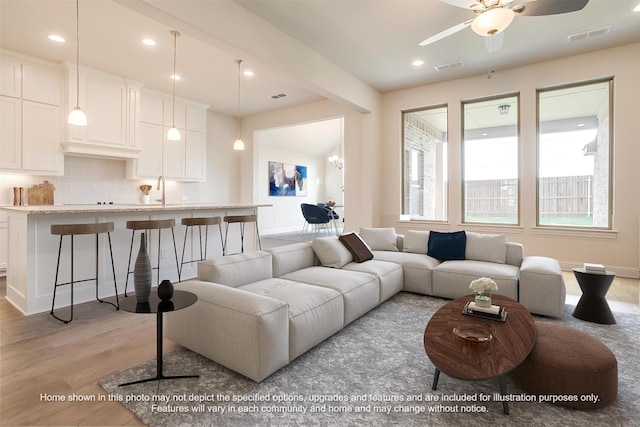 living room featuring light wood-type flooring, visible vents, baseboards, and recessed lighting