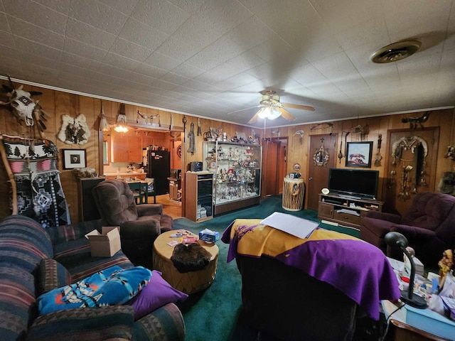 carpeted living room featuring wood walls, crown molding, and ceiling fan