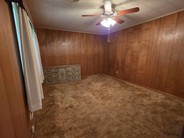 unfurnished room with wooden walls, carpet floors, and ceiling fan