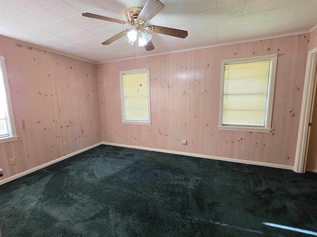spare room featuring ornamental molding, dark carpet, and ceiling fan