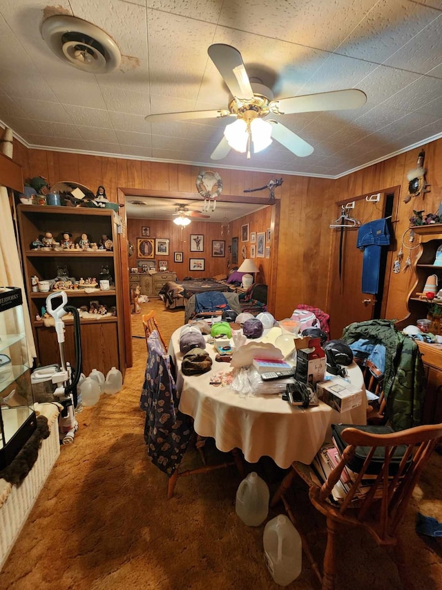 carpeted dining room with wood walls and ceiling fan