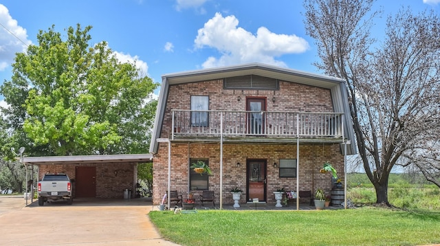 view of front facade with a balcony, a front yard, and a carport