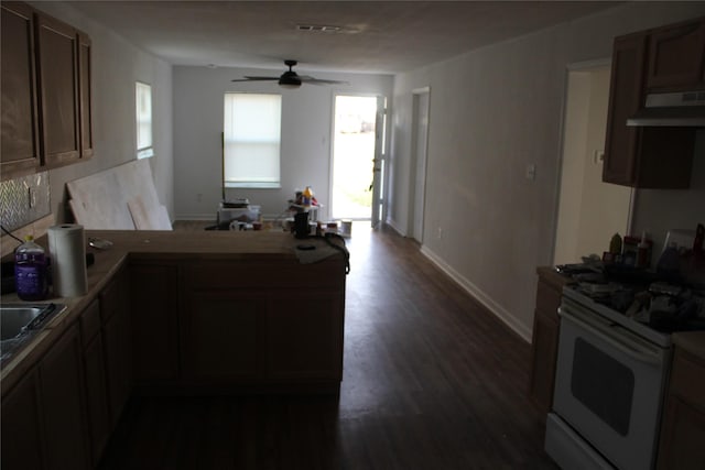 kitchen with ceiling fan, kitchen peninsula, white stove, and dark wood-type flooring