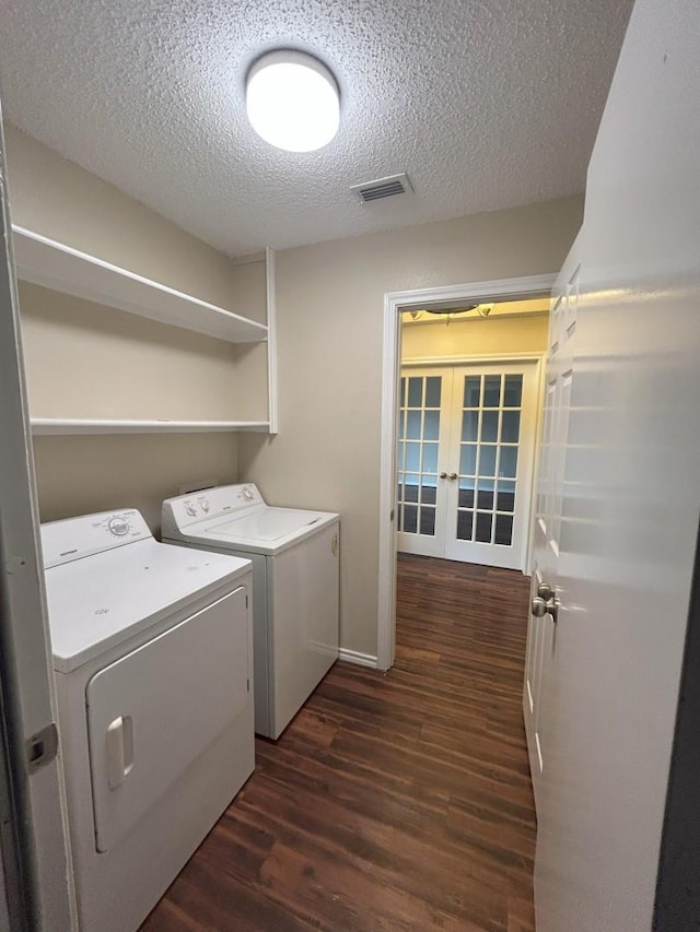 laundry area featuring a textured ceiling, independent washer and dryer, dark wood-type flooring, and french doors