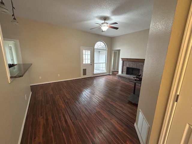 unfurnished living room featuring a textured ceiling, dark hardwood / wood-style floors, ceiling fan, and a fireplace