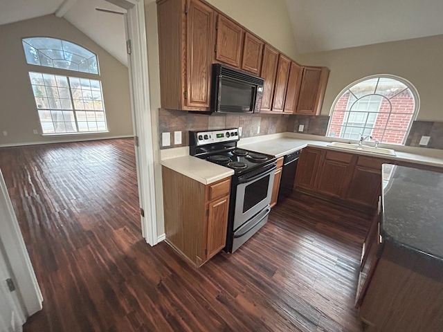 kitchen featuring lofted ceiling, dark wood-type flooring, black appliances, sink, and decorative backsplash