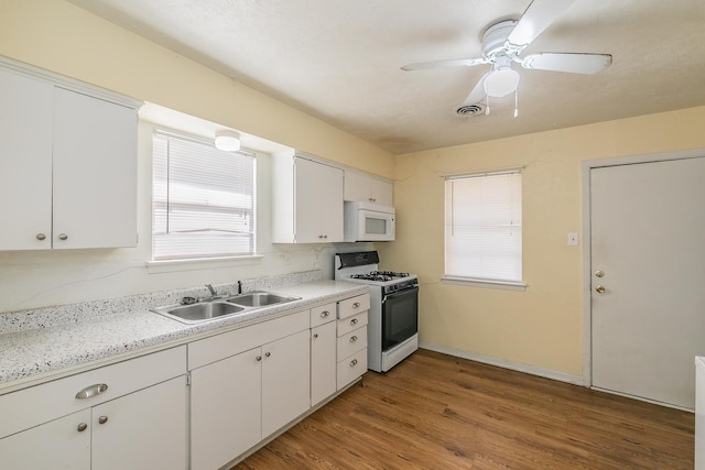 kitchen with light wood-type flooring, white appliances, sink, white cabinetry, and plenty of natural light