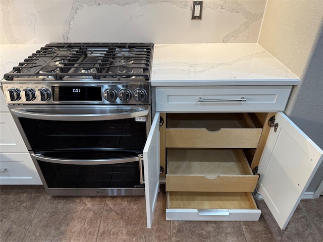 details with white cabinetry, light stone counters, gas range, and decorative backsplash