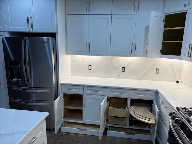 kitchen with tasteful backsplash, gas stove, fridge with ice dispenser, and light stone counters