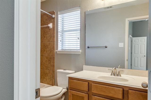 full bathroom featuring vanity, tiled shower / bath, and toilet