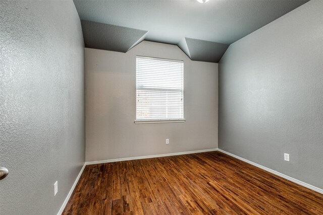 unfurnished room featuring hardwood / wood-style flooring and lofted ceiling