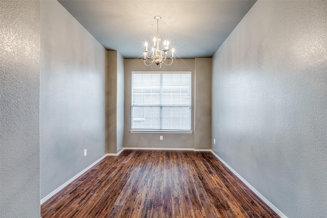 unfurnished room with dark wood-type flooring and an inviting chandelier