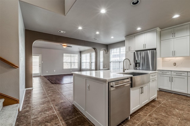 kitchen featuring stainless steel appliances, an island with sink, and white cabinets