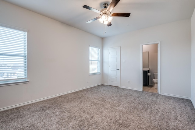 unfurnished bedroom with light carpet, ensuite bathroom, and ceiling fan