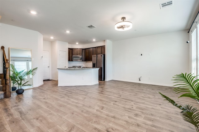 kitchen featuring light stone countertops, dark brown cabinets, stainless steel appliances, and light hardwood / wood-style floors