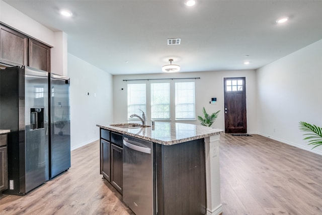 kitchen with sink, a kitchen island with sink, dark brown cabinets, appliances with stainless steel finishes, and light wood-type flooring