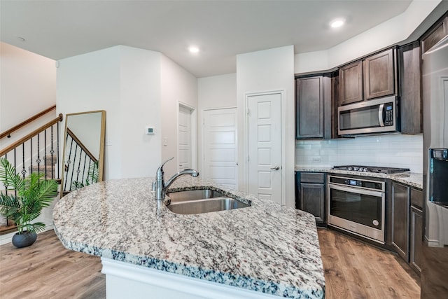 kitchen featuring sink, light stone countertops, stainless steel appliances, and a kitchen island with sink