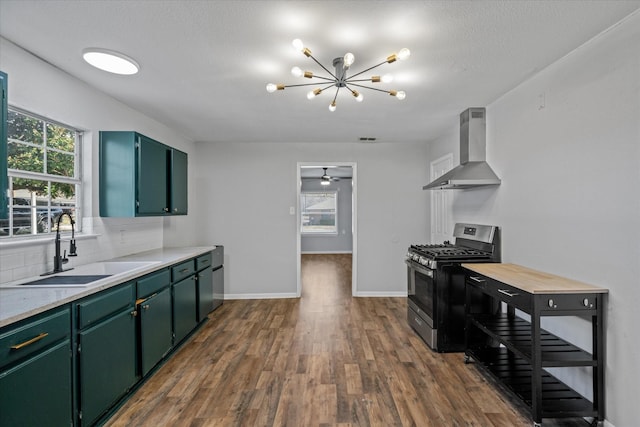 kitchen featuring sink, dark wood-type flooring, wall chimney range hood, tasteful backsplash, and stainless steel range with gas stovetop