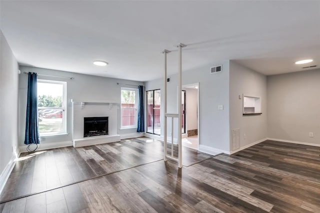 unfurnished living room with a fireplace, a wealth of natural light, and dark hardwood / wood-style floors