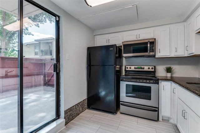 kitchen with appliances with stainless steel finishes, dark stone countertops, and white cabinetry