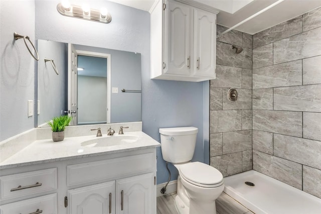 bathroom with toilet, vanity, and a tile shower