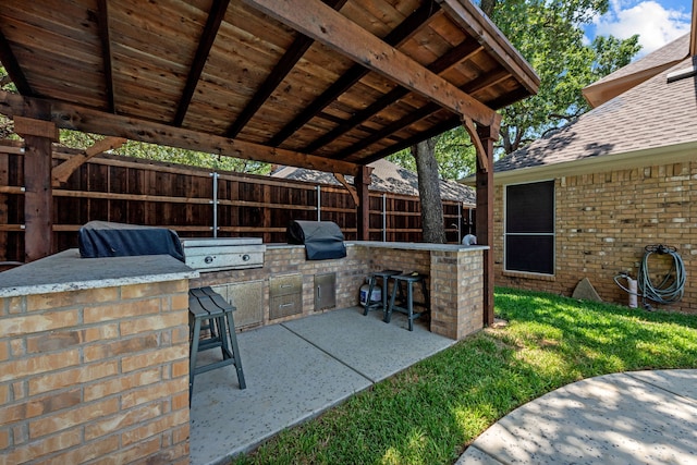 view of patio with area for grilling, an outdoor bar, and grilling area