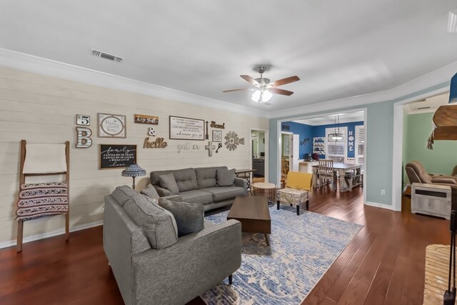 living room with crown molding, dark hardwood / wood-style flooring, ceiling fan, and a brick fireplace