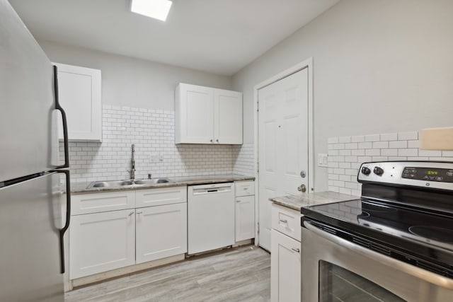 kitchen with light stone countertops, sink, light hardwood / wood-style floors, white cabinets, and appliances with stainless steel finishes