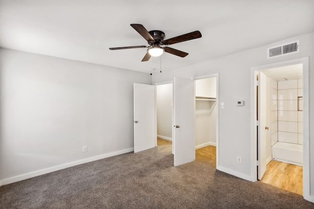 unfurnished bedroom with a closet, a walk in closet, ensuite bathroom, and ceiling fan