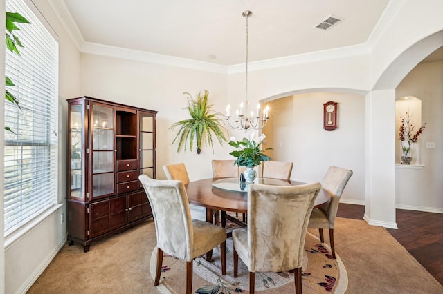 carpeted dining space featuring a chandelier and ornamental molding