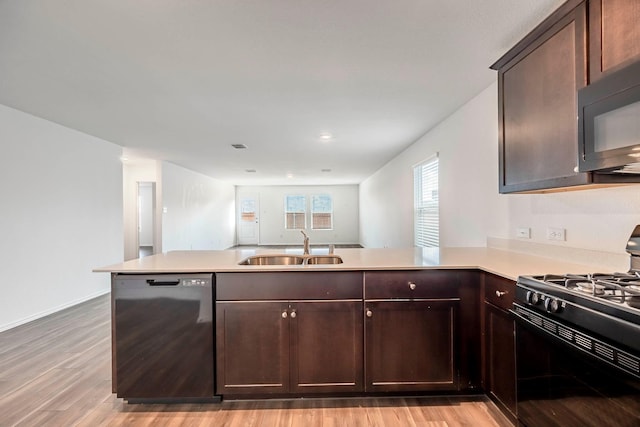 kitchen featuring kitchen peninsula, dark brown cabinetry, sink, black appliances, and light hardwood / wood-style flooring