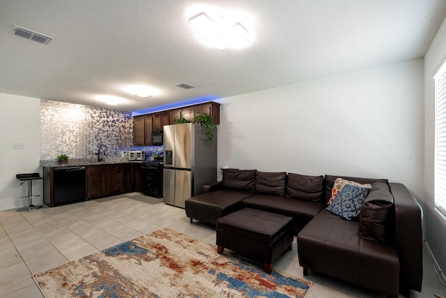 tiled living room with sink, plenty of natural light, and a textured ceiling