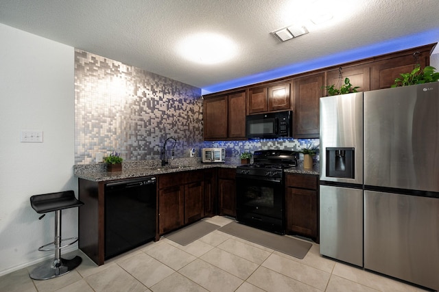 kitchen with sink, backsplash, dark stone counters, and black appliances