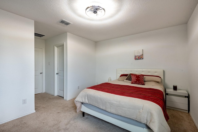 bedroom with light colored carpet and a textured ceiling