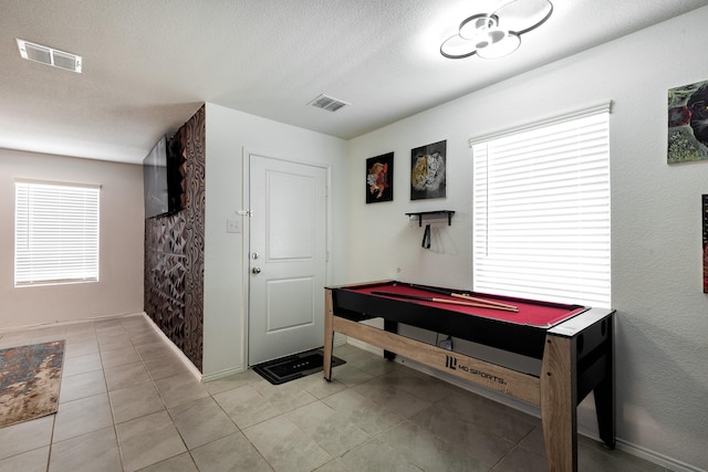 rec room featuring light tile patterned floors, pool table, and a textured ceiling